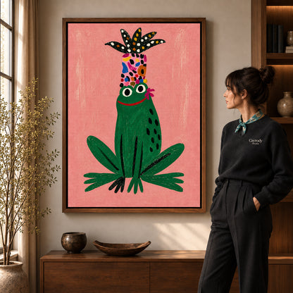 folk botanical frog canvas art in a walnut frame beside a standing woman and wooden console.