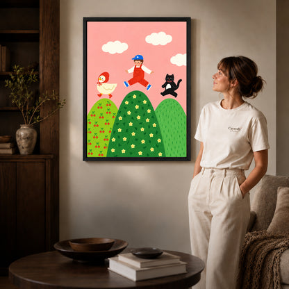 playful hilltop friends canvas art in a black frame beside a woman and round wooden table.