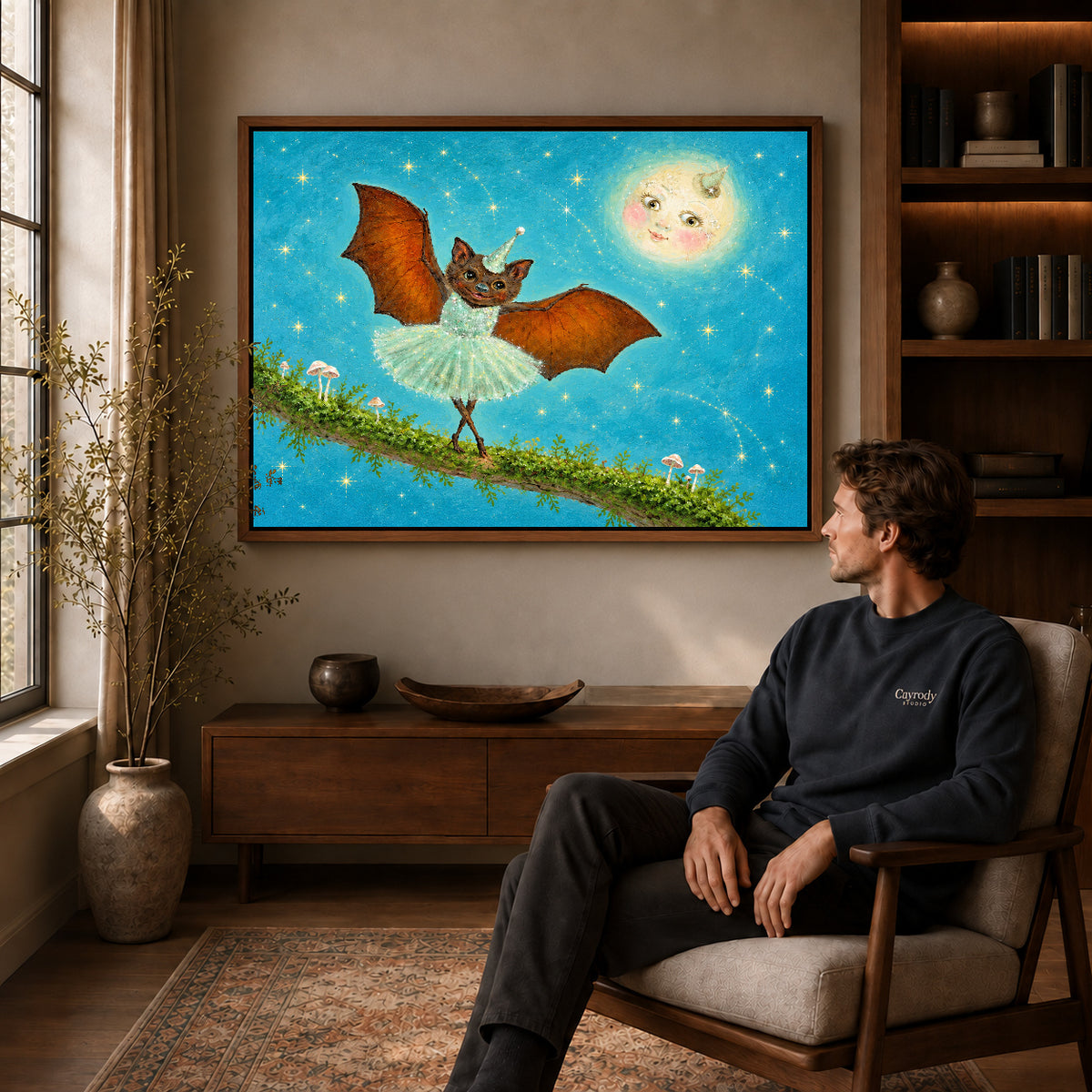 fantasy ballet bat canvas art in a walnut frame above a console beside a seated man.
