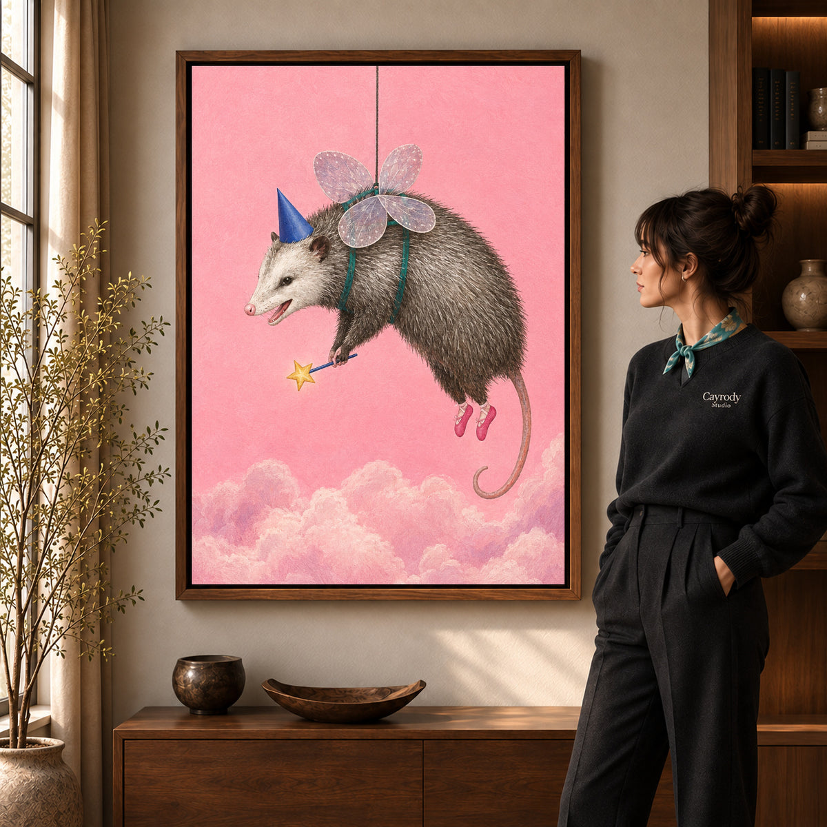 whimsical fairy opossum canvas art in a walnut frame beside a standing woman and wooden console.