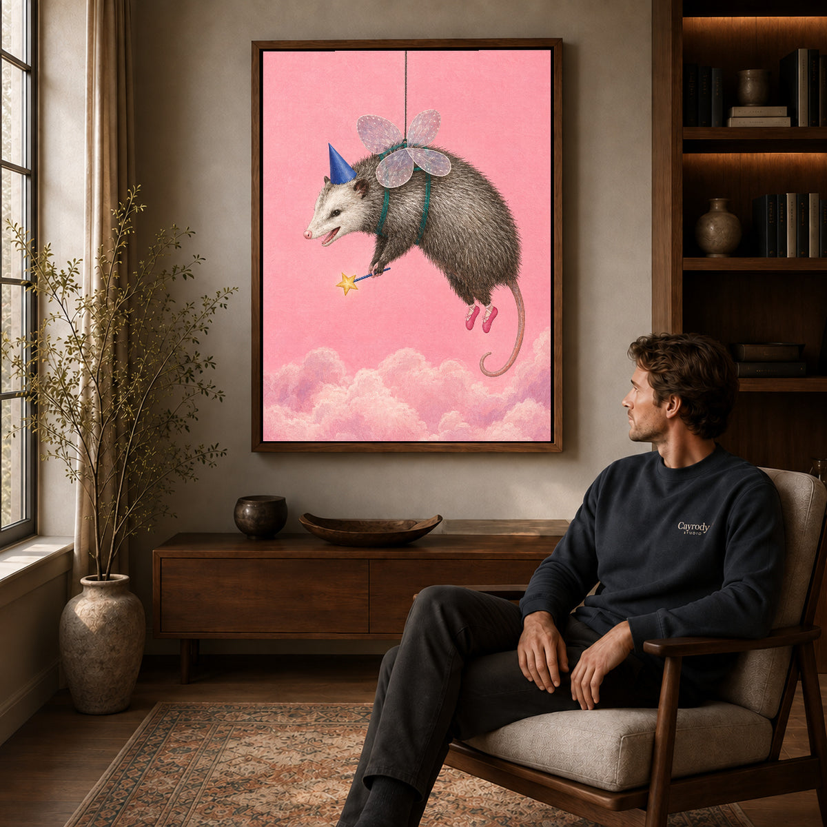 whimsical fairy opossum canvas art in a walnut frame above a console beside a seated man.