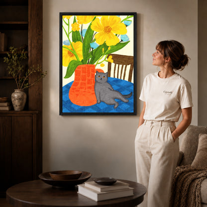 expressive floral cat canvas art in a black frame beside a woman and round wooden table.