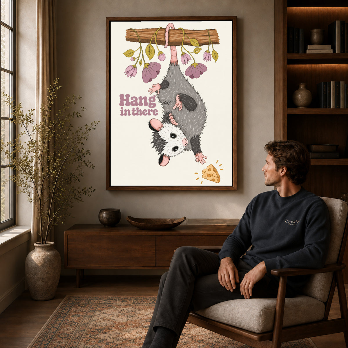 whimsical hanging opossum canvas art in a walnut frame above a console beside a seated man.