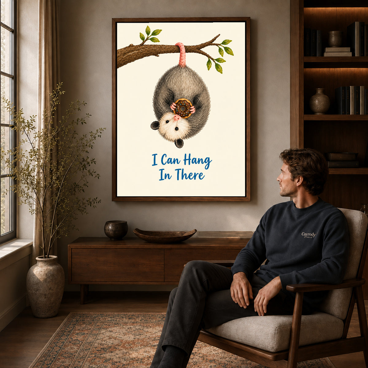 whimsical donut opossum canvas art in a walnut frame above a console beside a seated man.