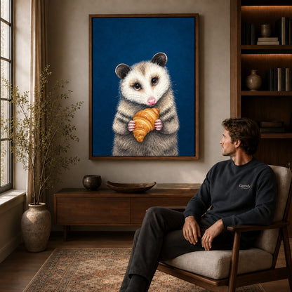 croissant opossum portrait canvas art in a walnut frame above a console beside a seated man.