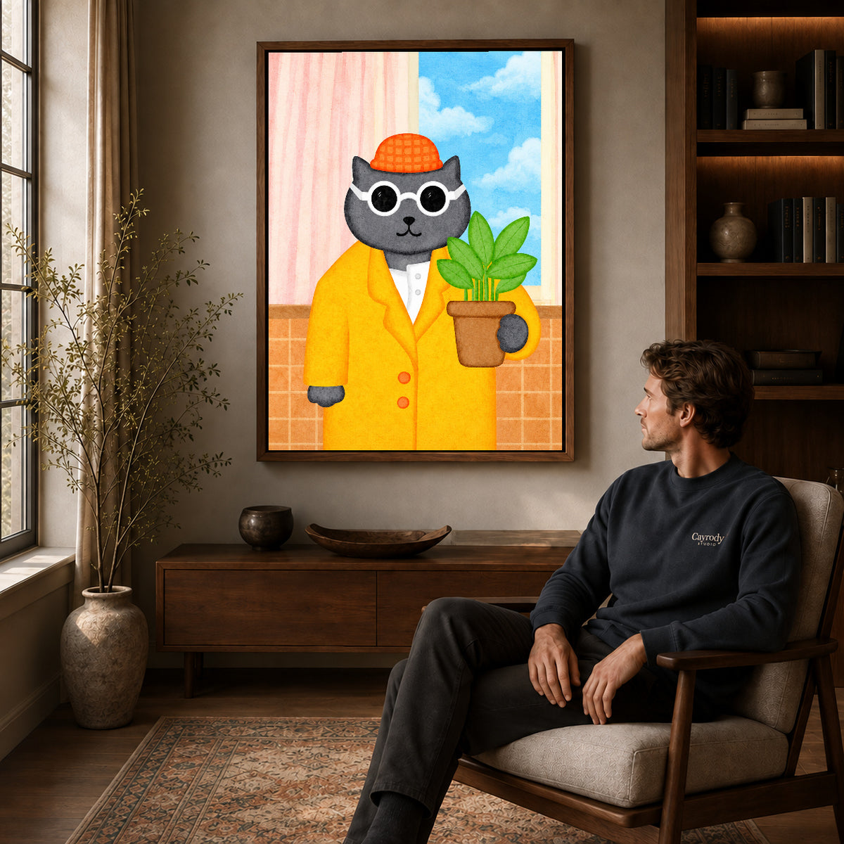 whimsical plant lover cat canvas art in a walnut frame above a console beside a seated man.