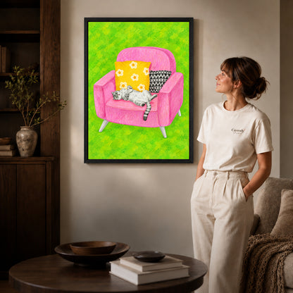 playful reclining cat canvas art in a black frame beside a woman and round wooden table.