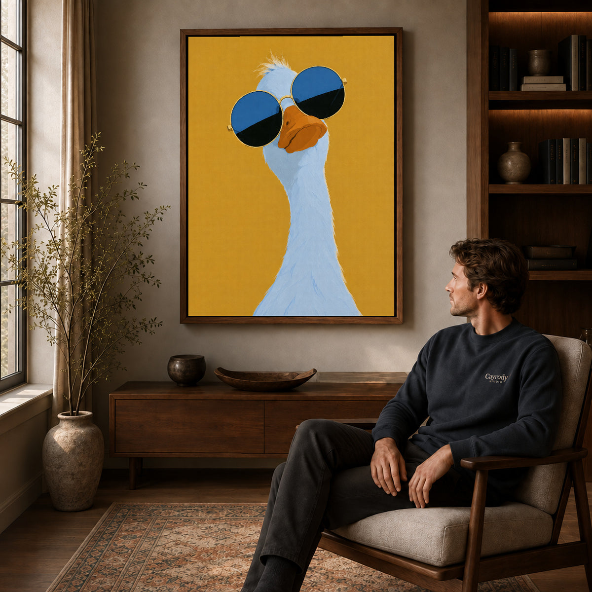 sunglasses goose portrait canvas art in a walnut frame above a console beside a seated man.