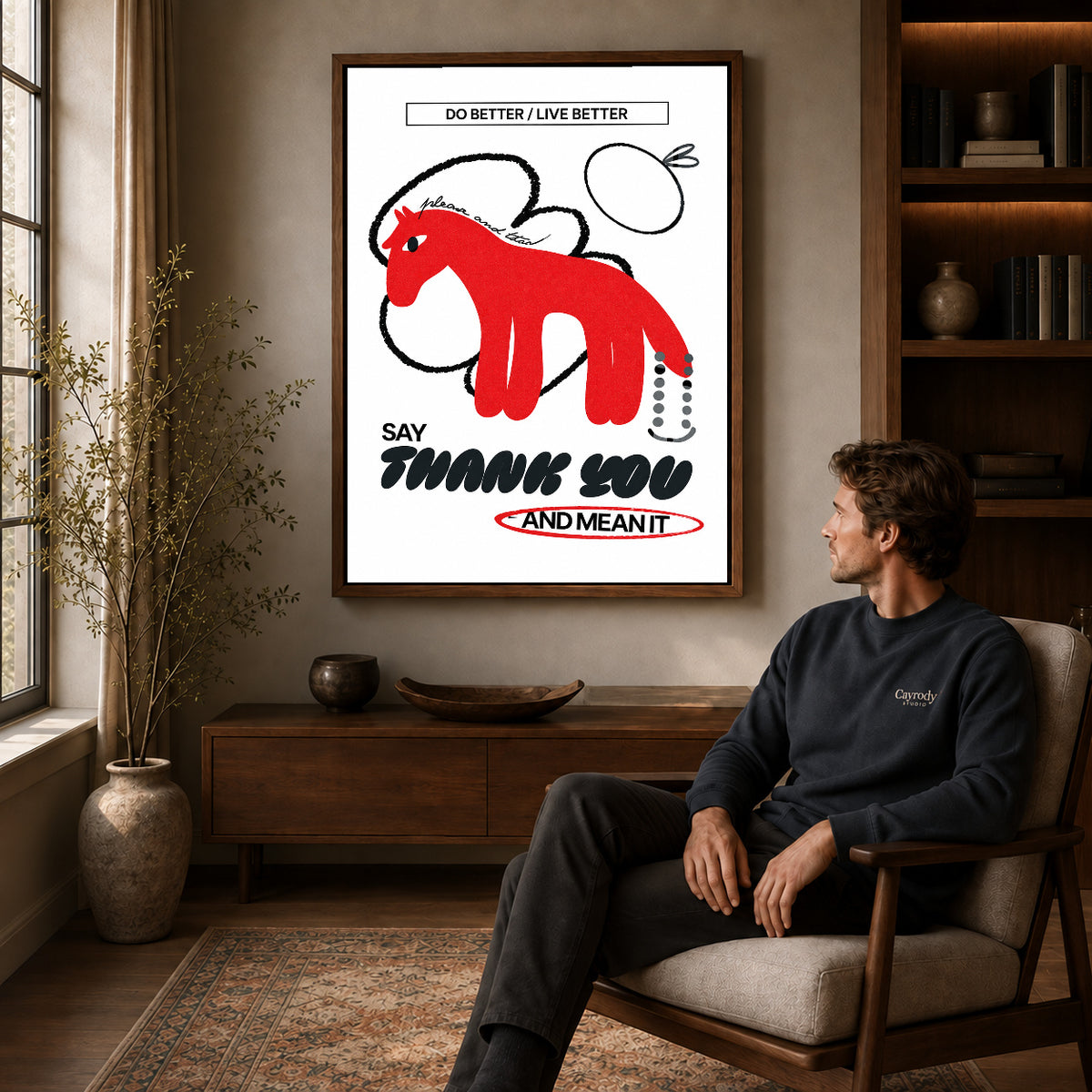 graphic gratitude horse canvas art in a walnut frame above a console beside a seated man.