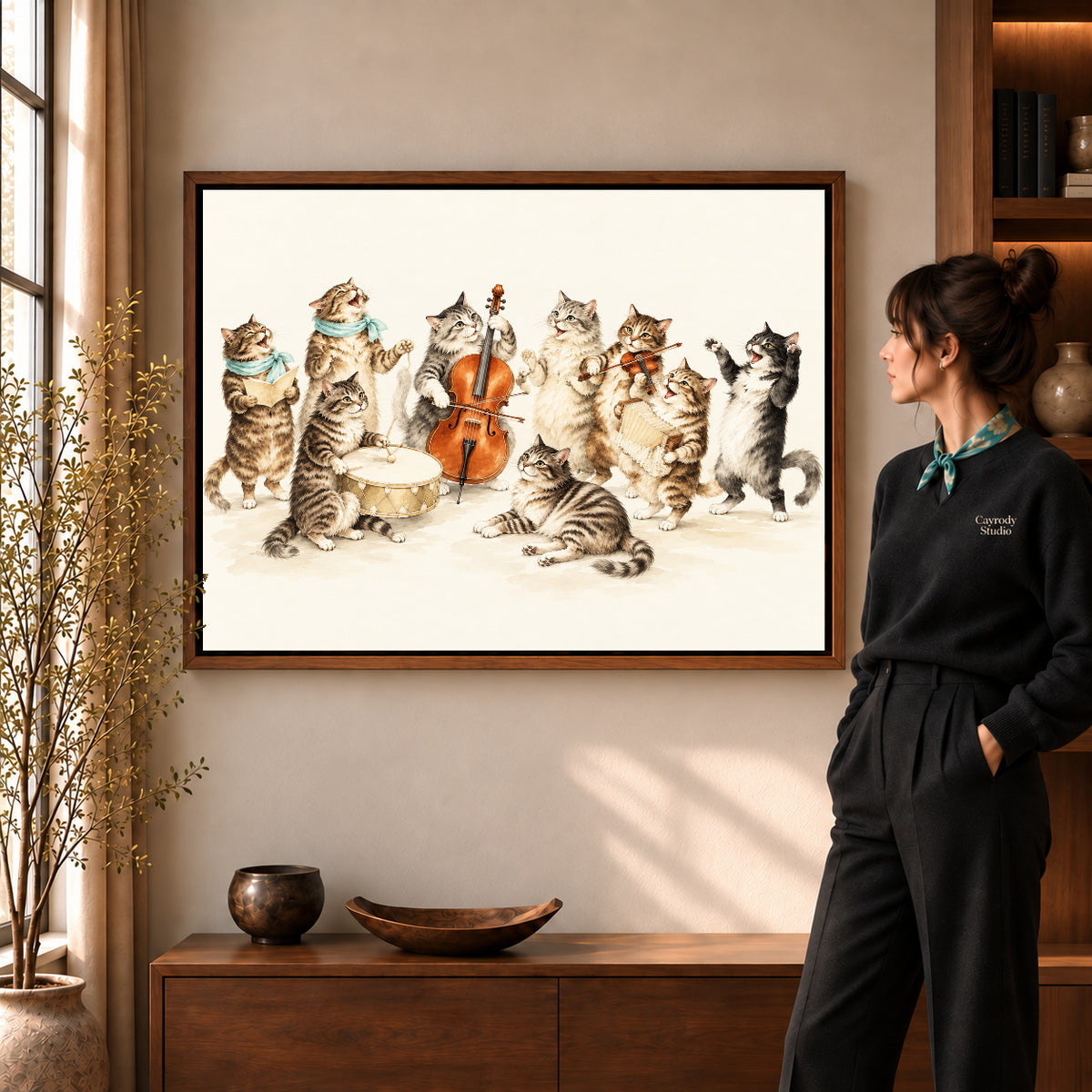 vintage cat orchestra canvas art in a walnut frame beside a standing woman and wooden console.
