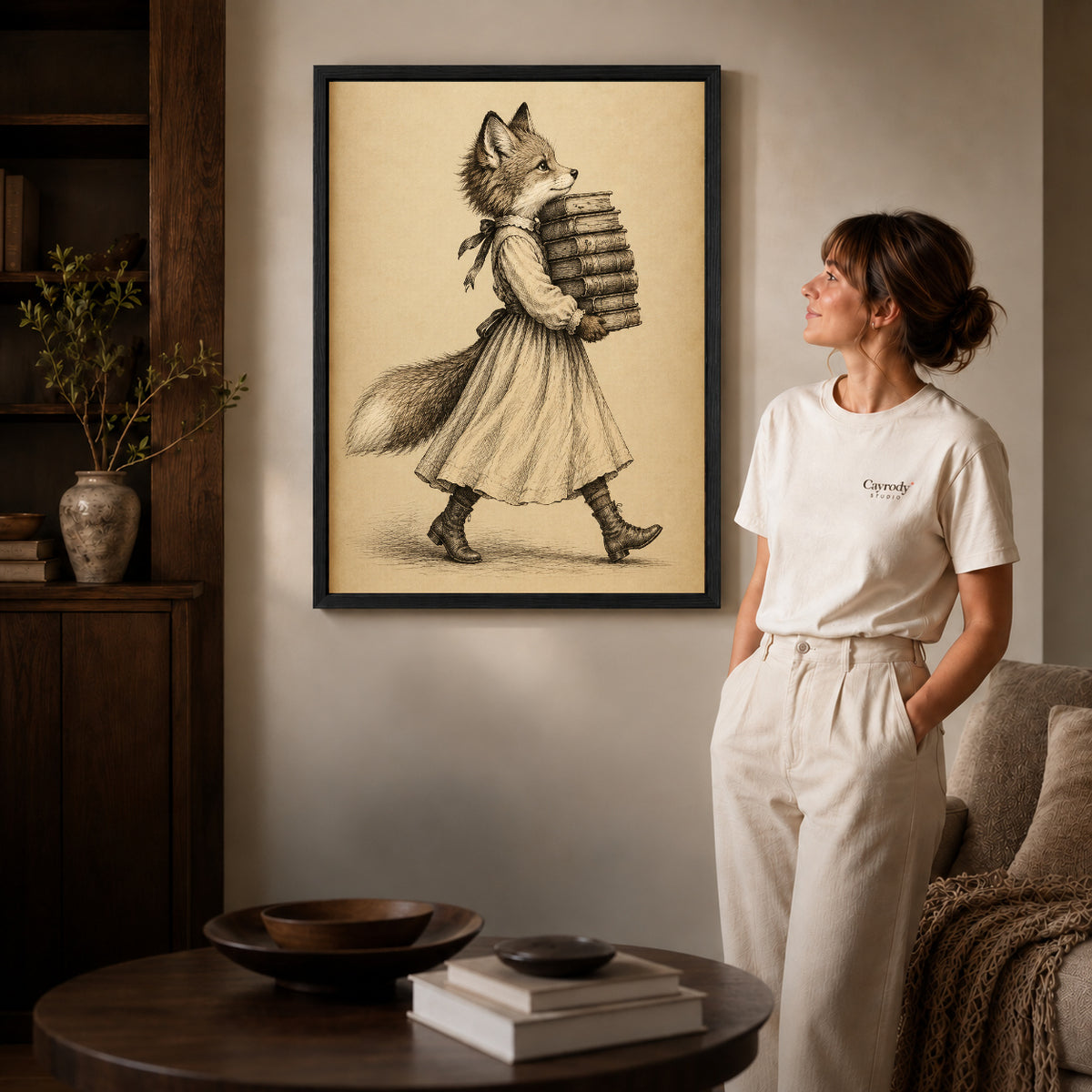 vintage bookish fox canvas art in a black frame beside a woman and round wooden table.