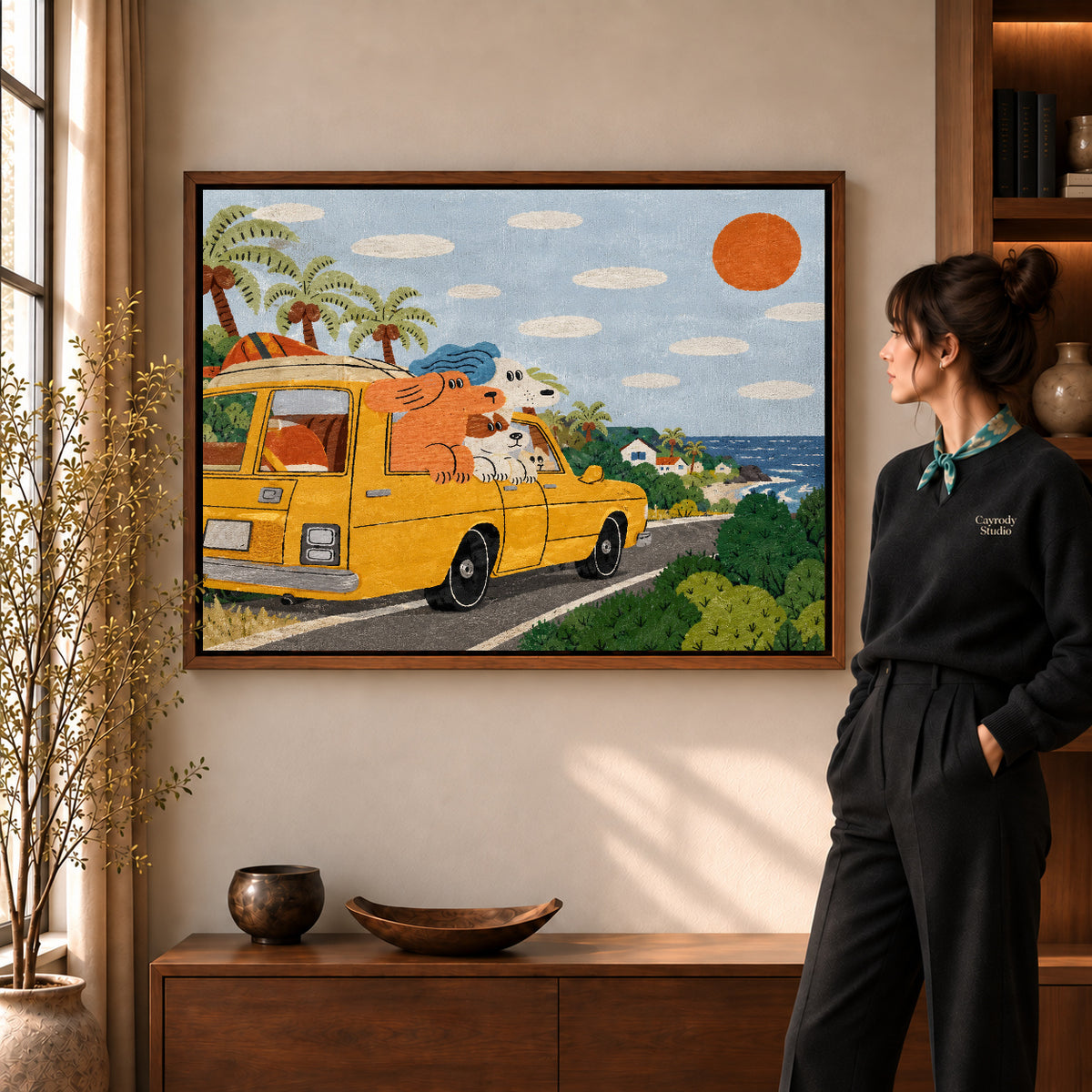 coastal camper dogs canvas art in a walnut frame beside a standing woman and wooden console.