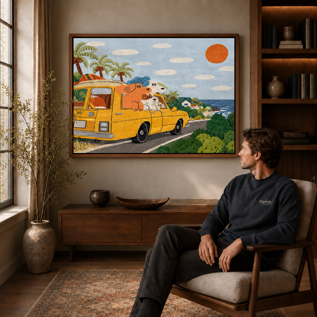 coastal camper dogs canvas art in a walnut frame above a console beside a seated man.