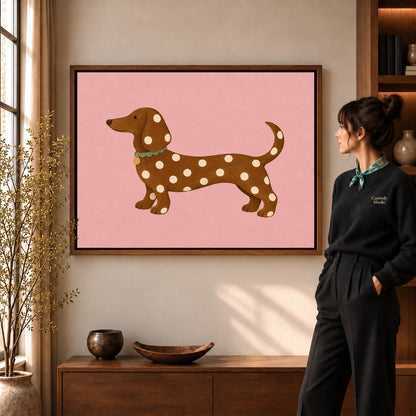 polka dot dachshund canvas art in a walnut frame beside a standing woman and wooden console.
