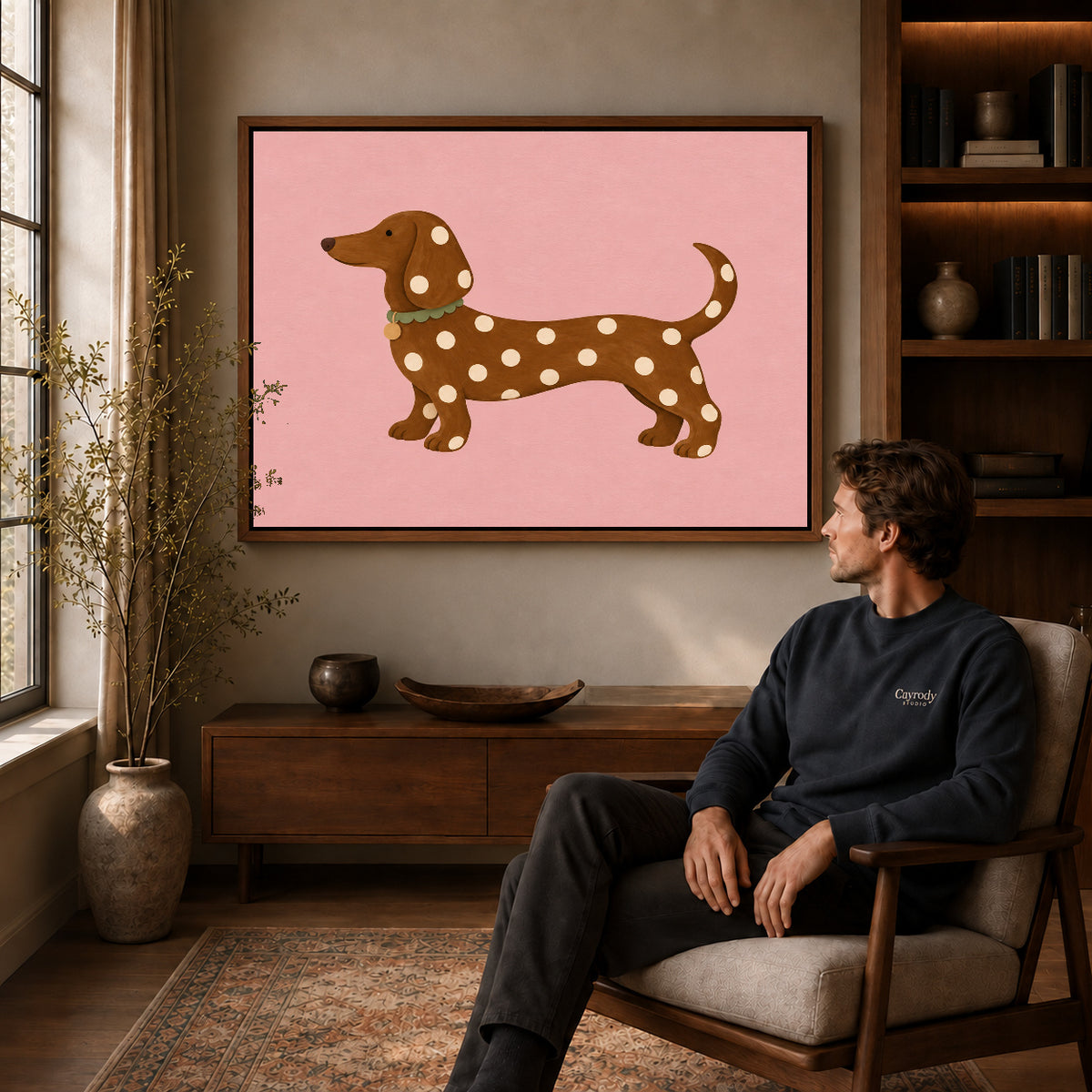 polka dot dachshund canvas art in a walnut frame above a console beside a seated man.