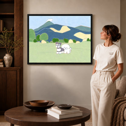 peaceful mountain dogs canvas art in a black frame beside a woman and round wooden table.