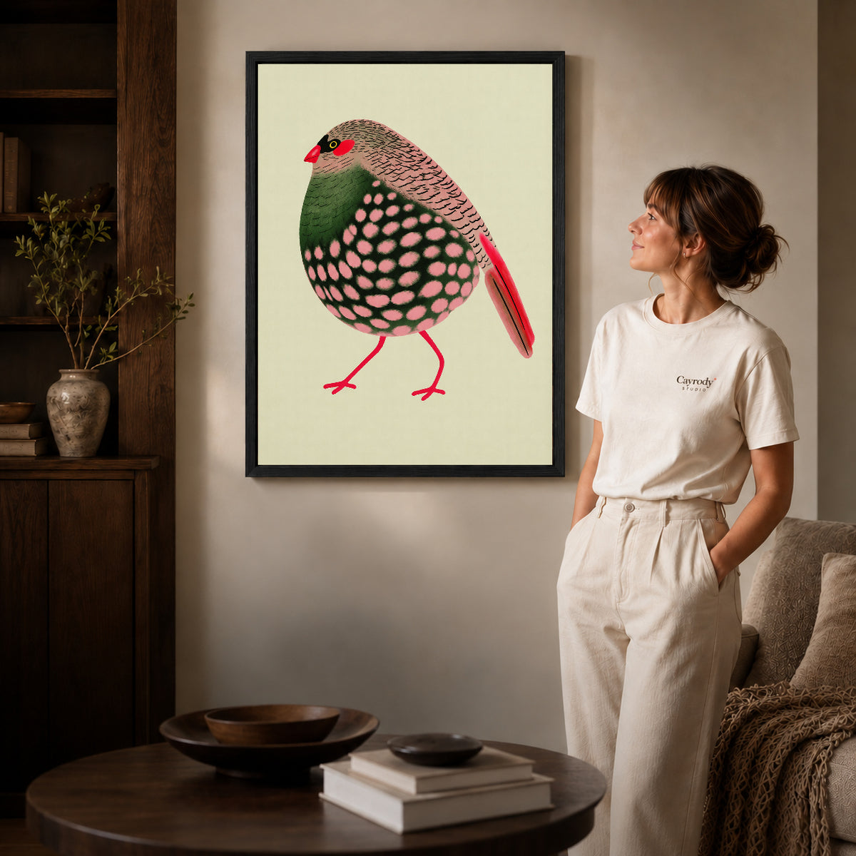 decorative spotted finch canvas art shown in the black frame option against a softly lit wall.