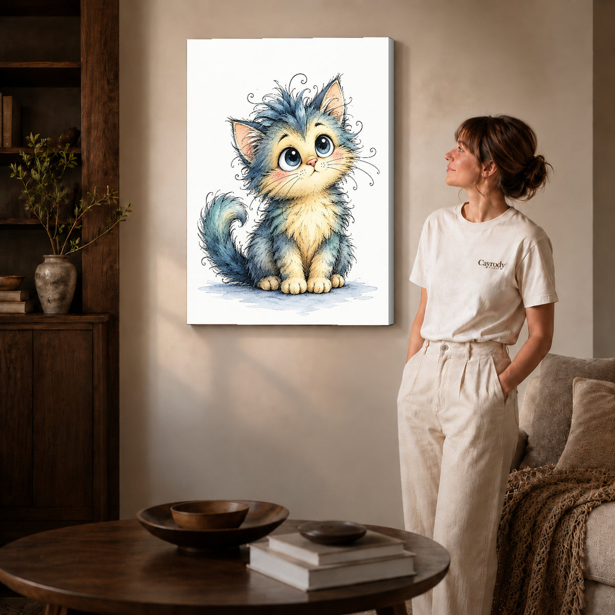 whimsical fluffy kitten canvas art on gallery-wrapped canvas with natural edge shading beside a standing woman.