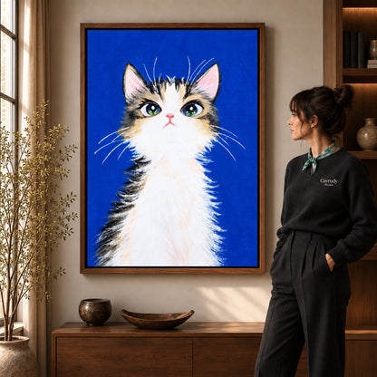 gentle blue kitten canvas art in a walnut frame beside a standing woman and wooden console.
