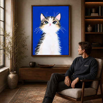 gentle blue kitten canvas art in a walnut frame above a console beside a seated man.