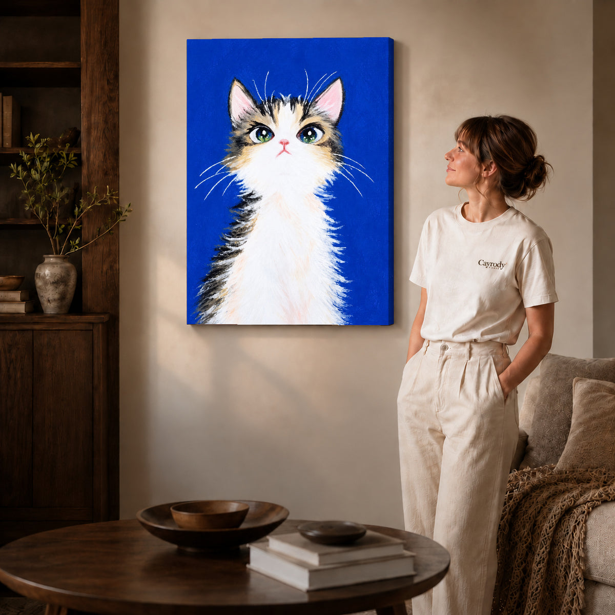 gentle blue kitten canvas art on gallery-wrapped canvas with natural edge shading beside a standing woman.