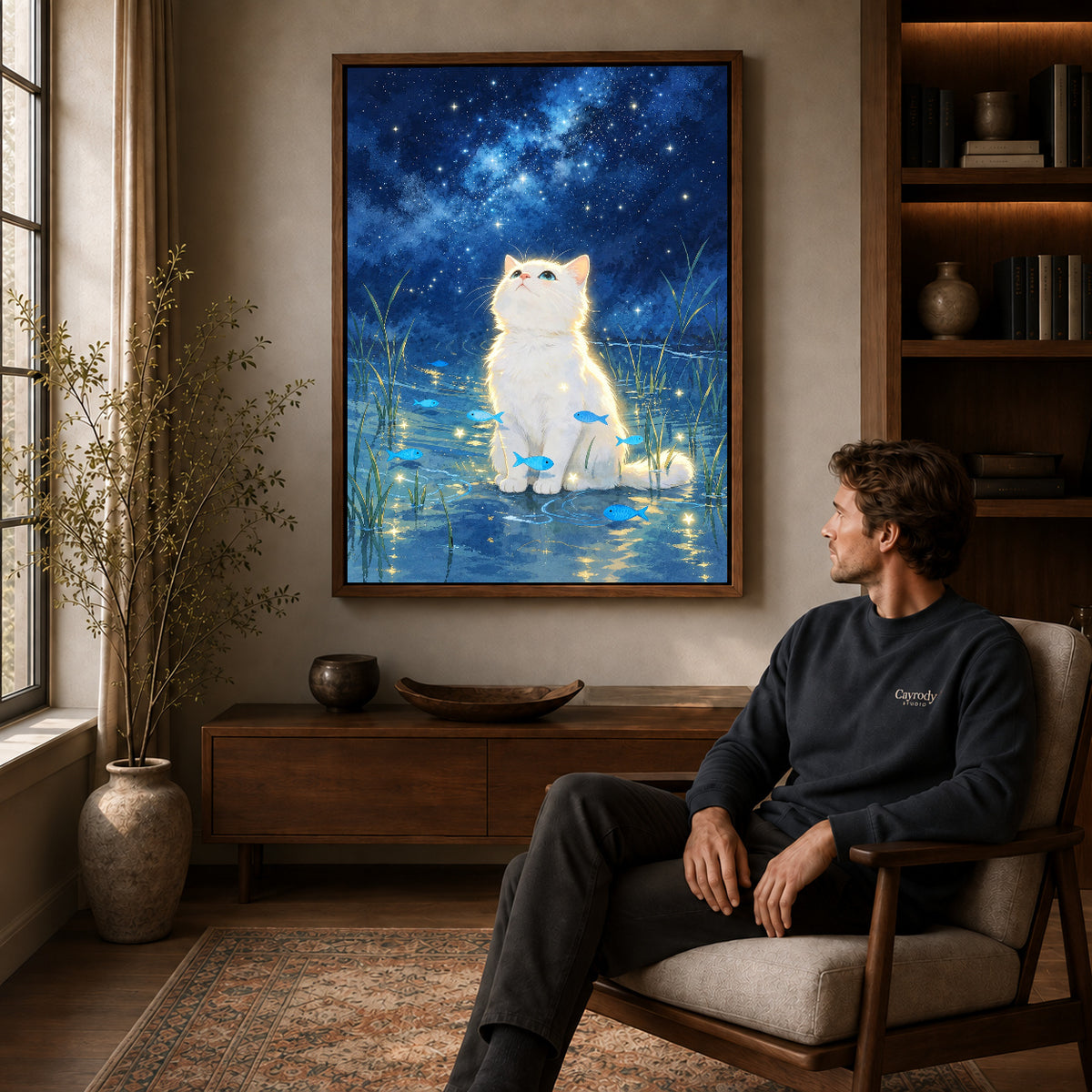 dreamy starlight kitten canvas art in a walnut frame above a console beside a seated man.