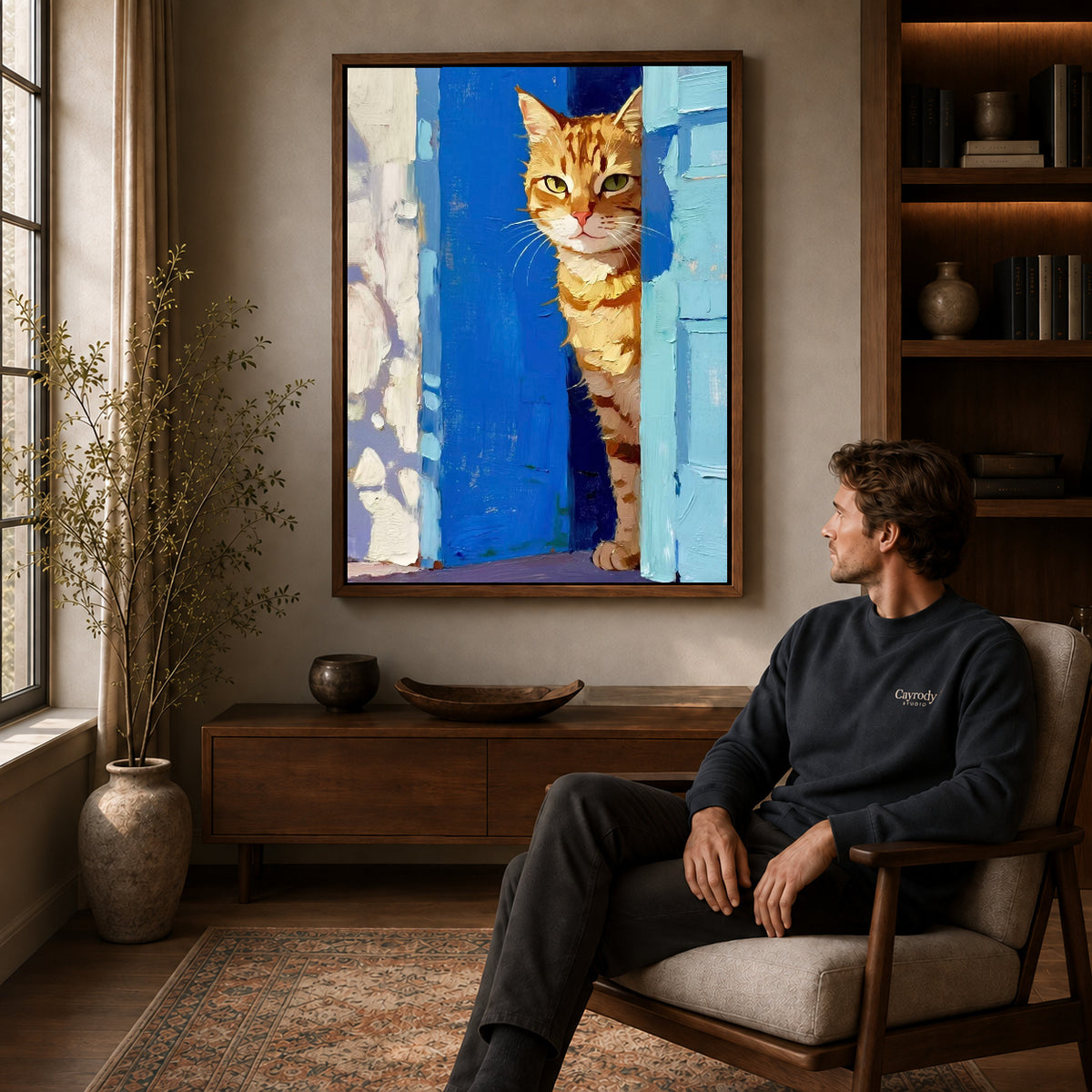 painterly doorway cat canvas art in a walnut frame above a console beside a seated man.