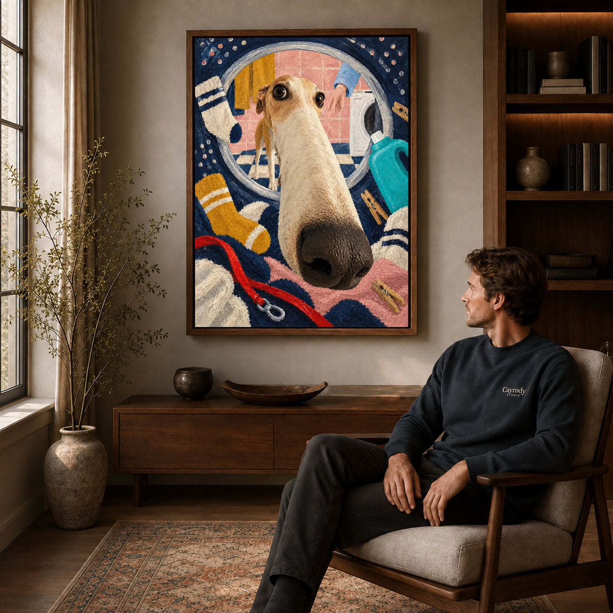 playful laundry dog canvas art in a walnut frame above a console beside a seated man.