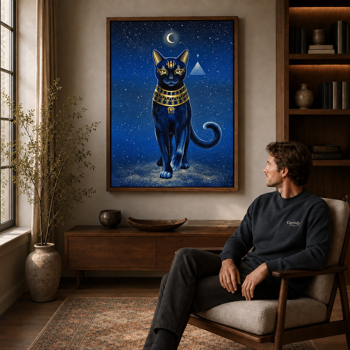 celestial golden cat canvas art in a walnut frame above a console beside a seated man.