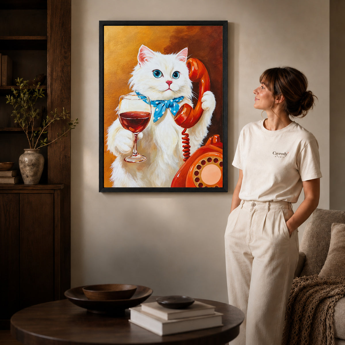 vintage telephone wine cat canvas art in a black frame beside a woman and round wooden table.