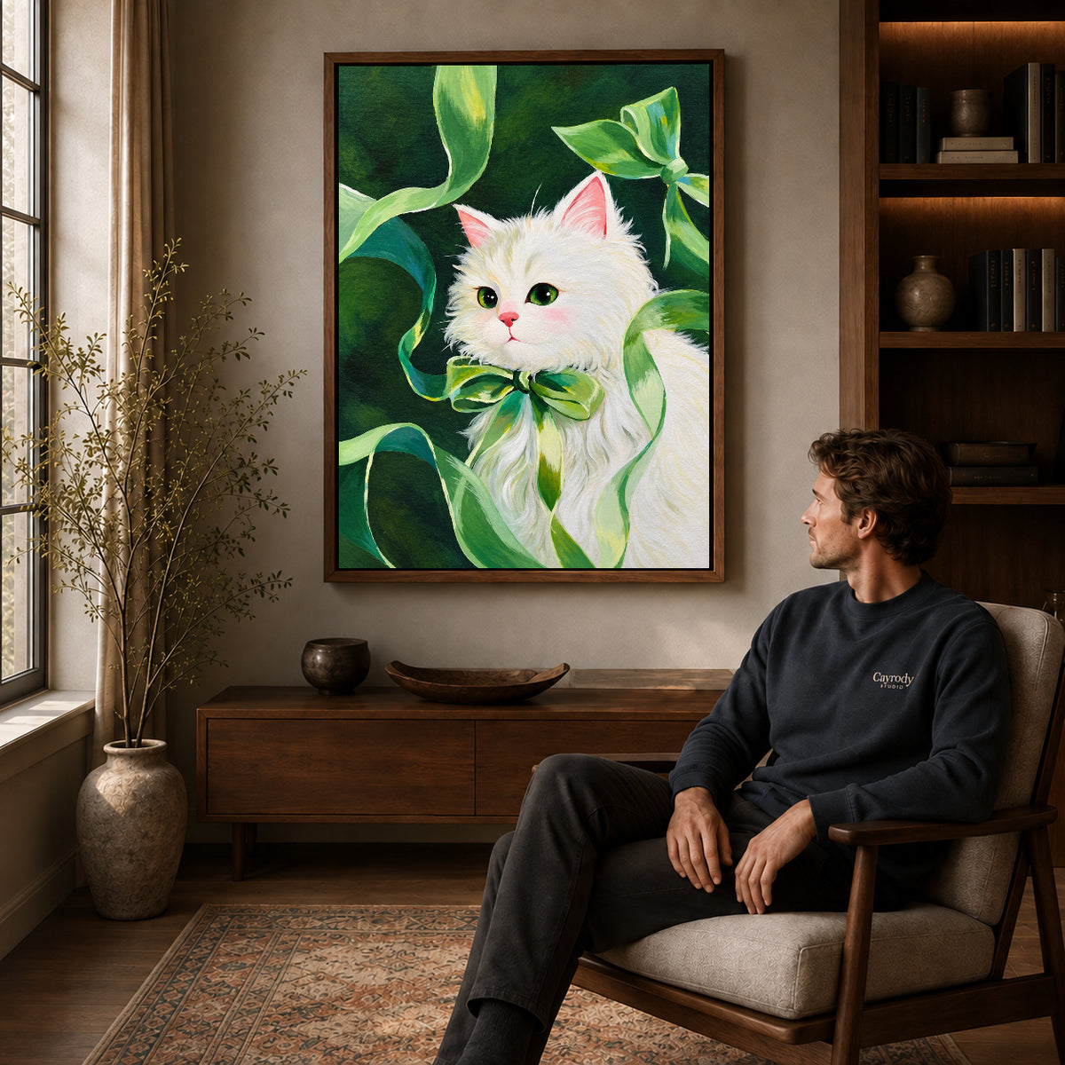 green ribbon kitten canvas art in a walnut frame above a console beside a seated man.