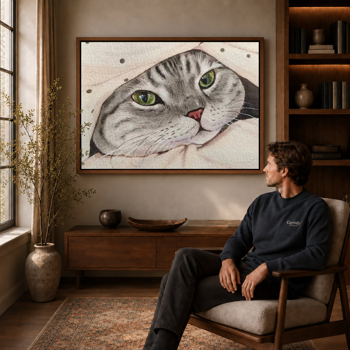 cozy blanket tabby canvas art in a walnut frame above a console beside a seated man.
