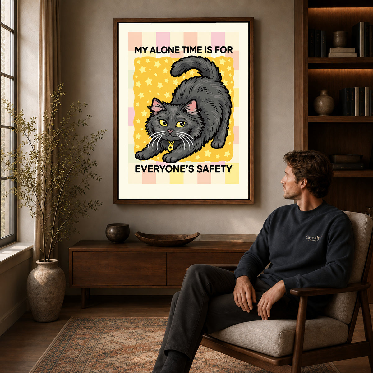 playful alone time cat canvas art in a walnut frame above a console beside a seated man.