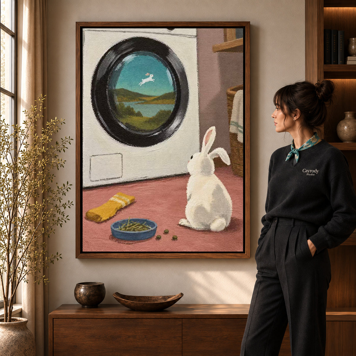 dreamy laundry rabbit canvas art in a walnut frame beside a standing woman and wooden console.
