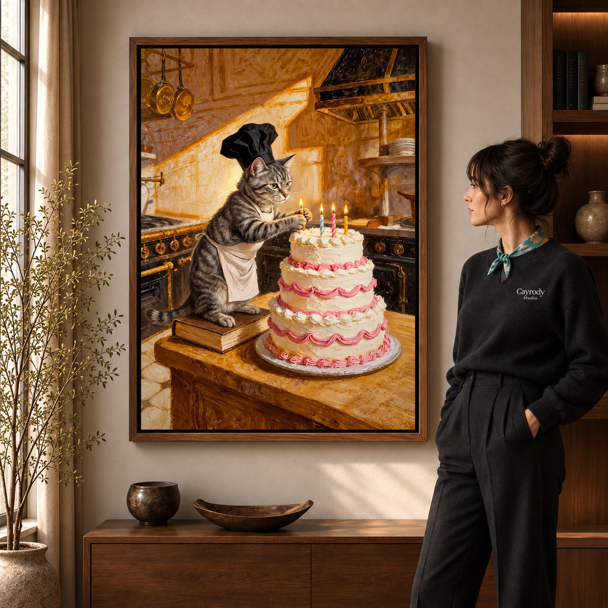 warm birthday baker cat canvas art in a walnut frame beside a standing woman and wooden console.