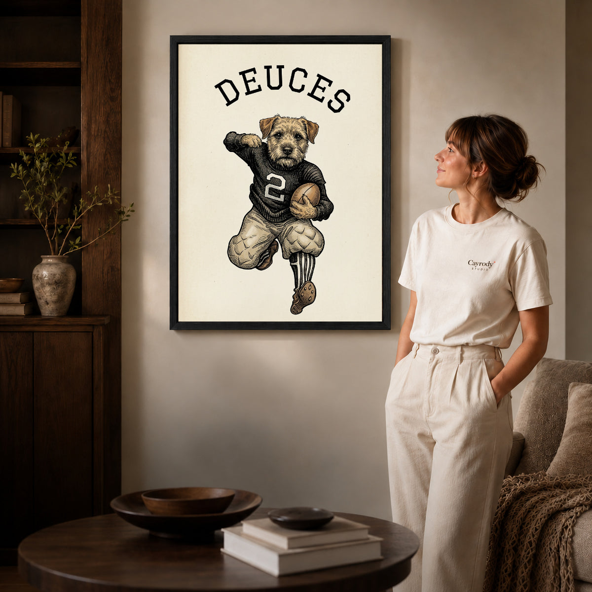 vintage football terrier canvas art in a black frame beside a woman and round wooden table.