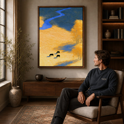 golden meadow cows canvas art in a walnut frame above a console beside a seated man.