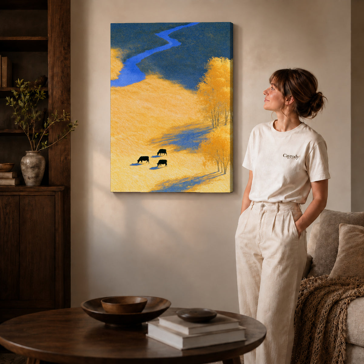 golden meadow cows canvas art on gallery-wrapped canvas with natural edge shading beside a standing woman.