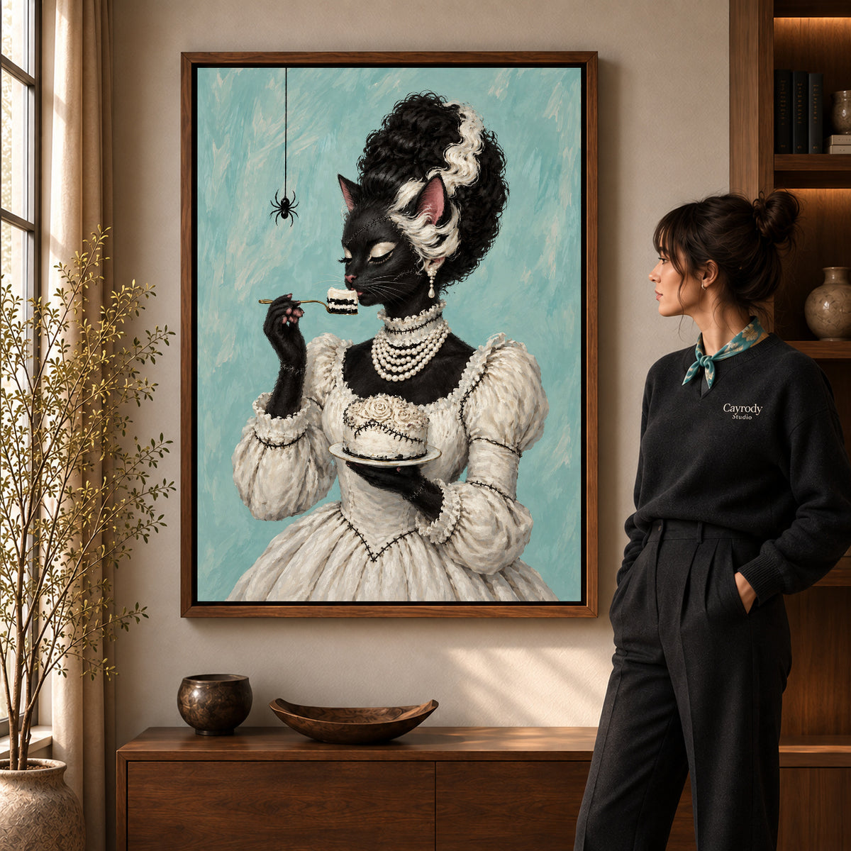 gothic cake cat canvas art in a walnut frame beside a standing woman and wooden console.