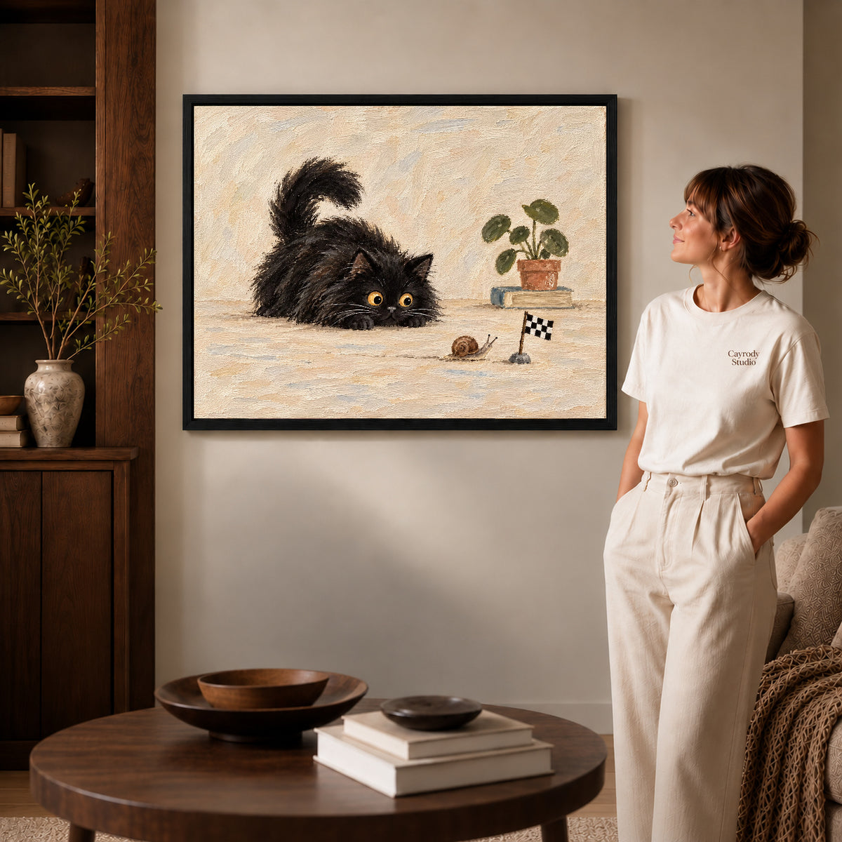 curious cat snail race canvas art in a black frame beside a woman and round wooden table.