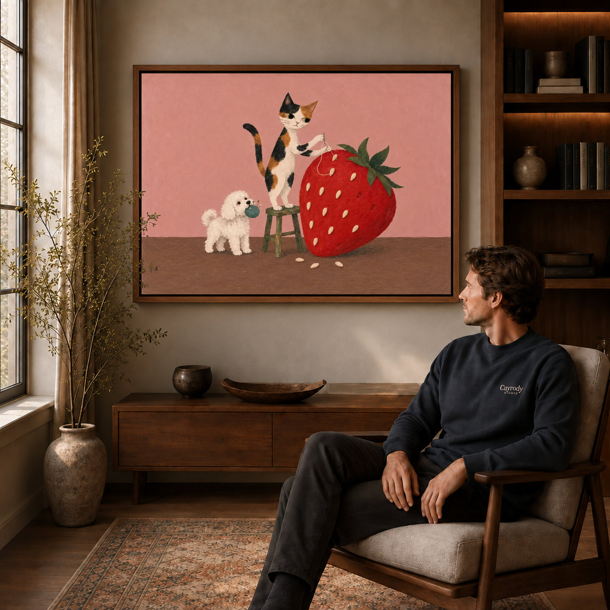 strawberry sewing friends canvas art in a walnut frame above a console beside a seated man.