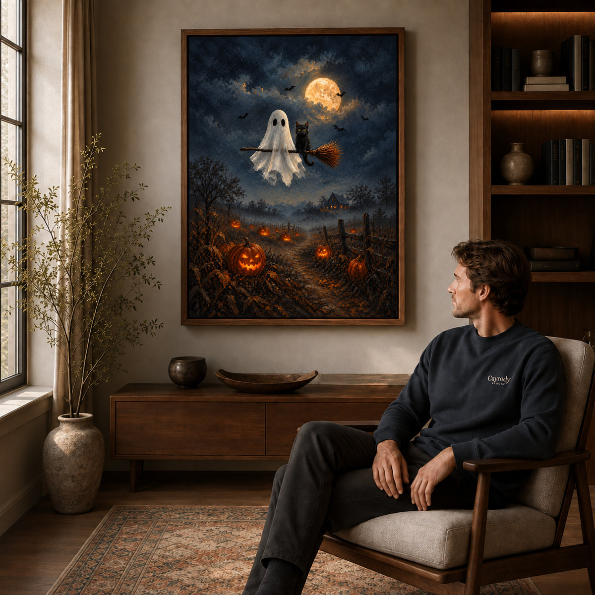 moonlit ghost cat ride canvas art in a walnut frame above a console beside a seated man.