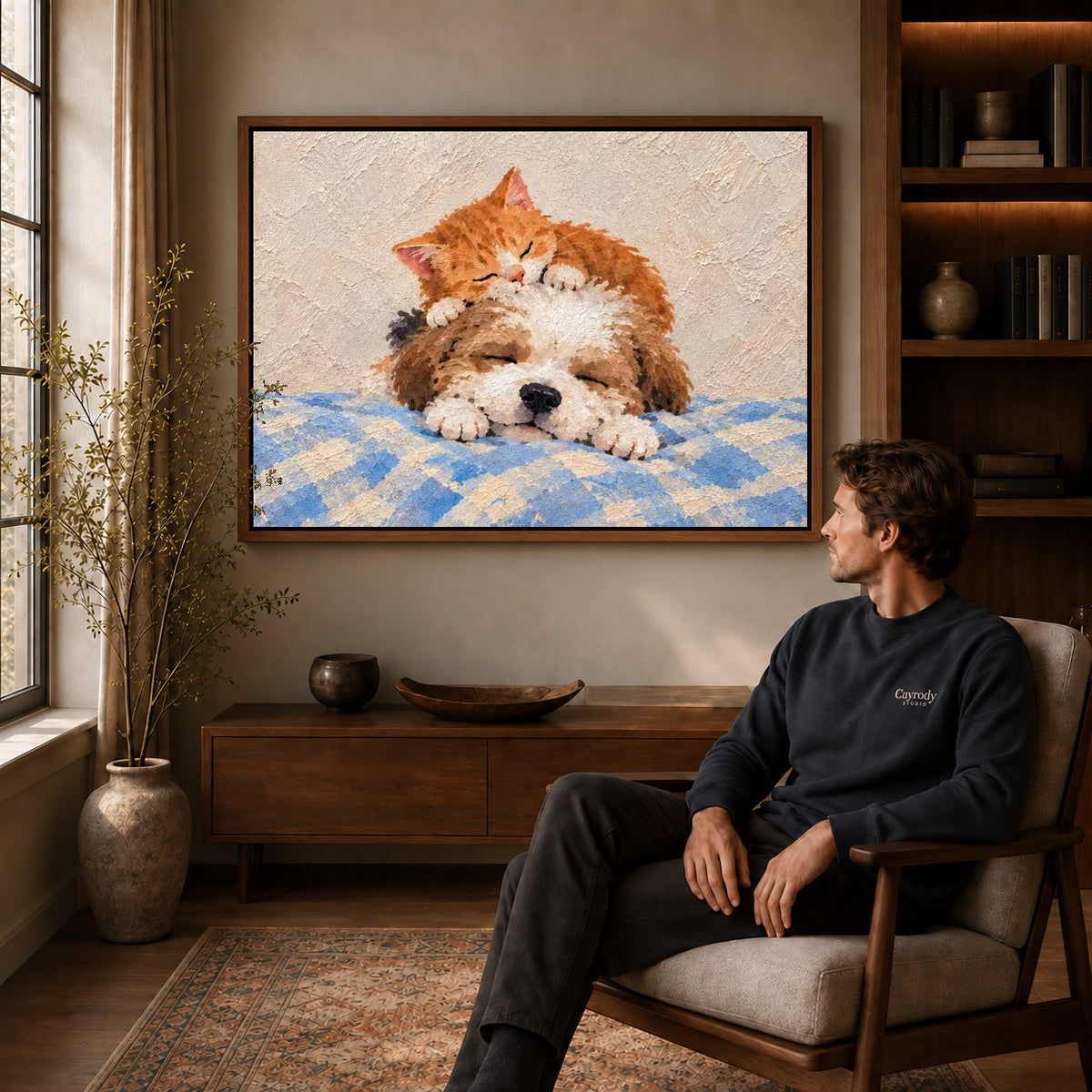 sleepy kitten puppy canvas art in a walnut frame above a console beside a seated man.