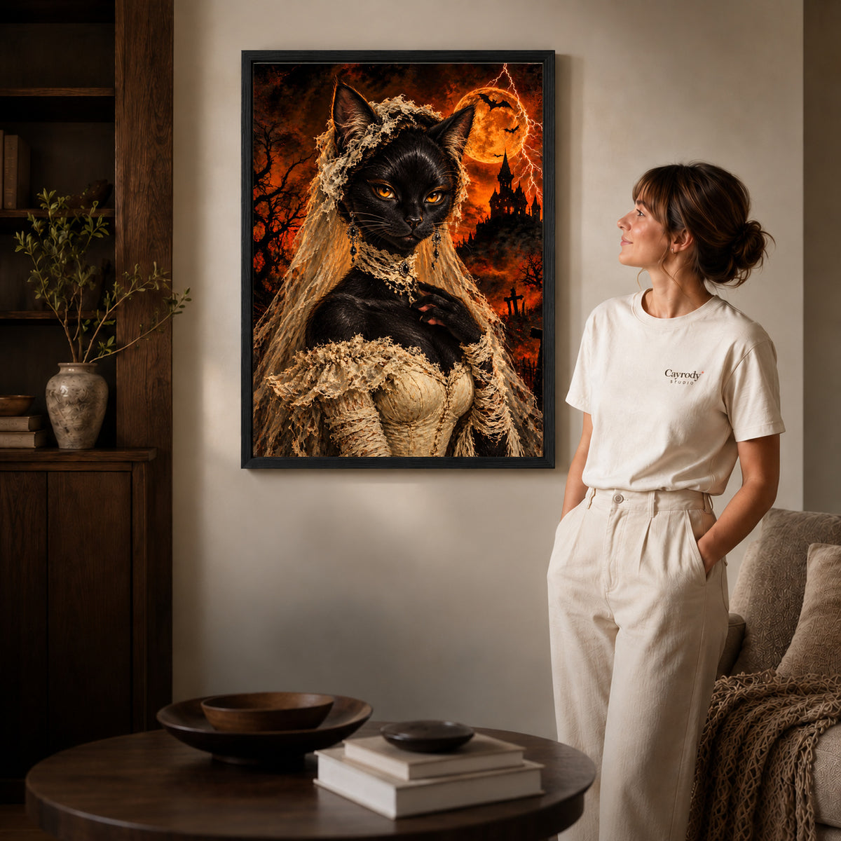 gothic lace cat canvas art in a black frame beside a woman and round wooden table.