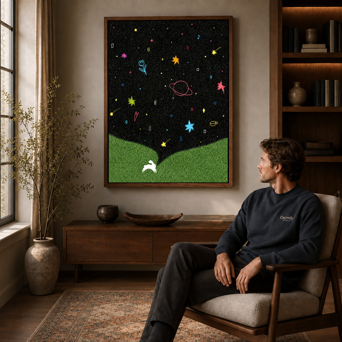 starry rabbit wonderland canvas art in a walnut frame above a console beside a seated man.