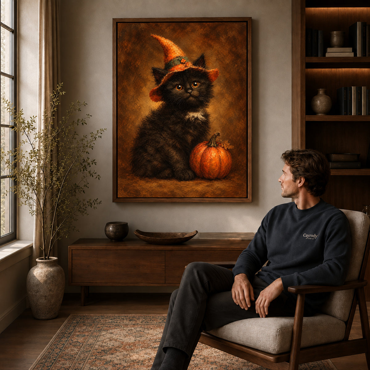 autumn witch kitten canvas art in a walnut frame above a console beside a seated man.