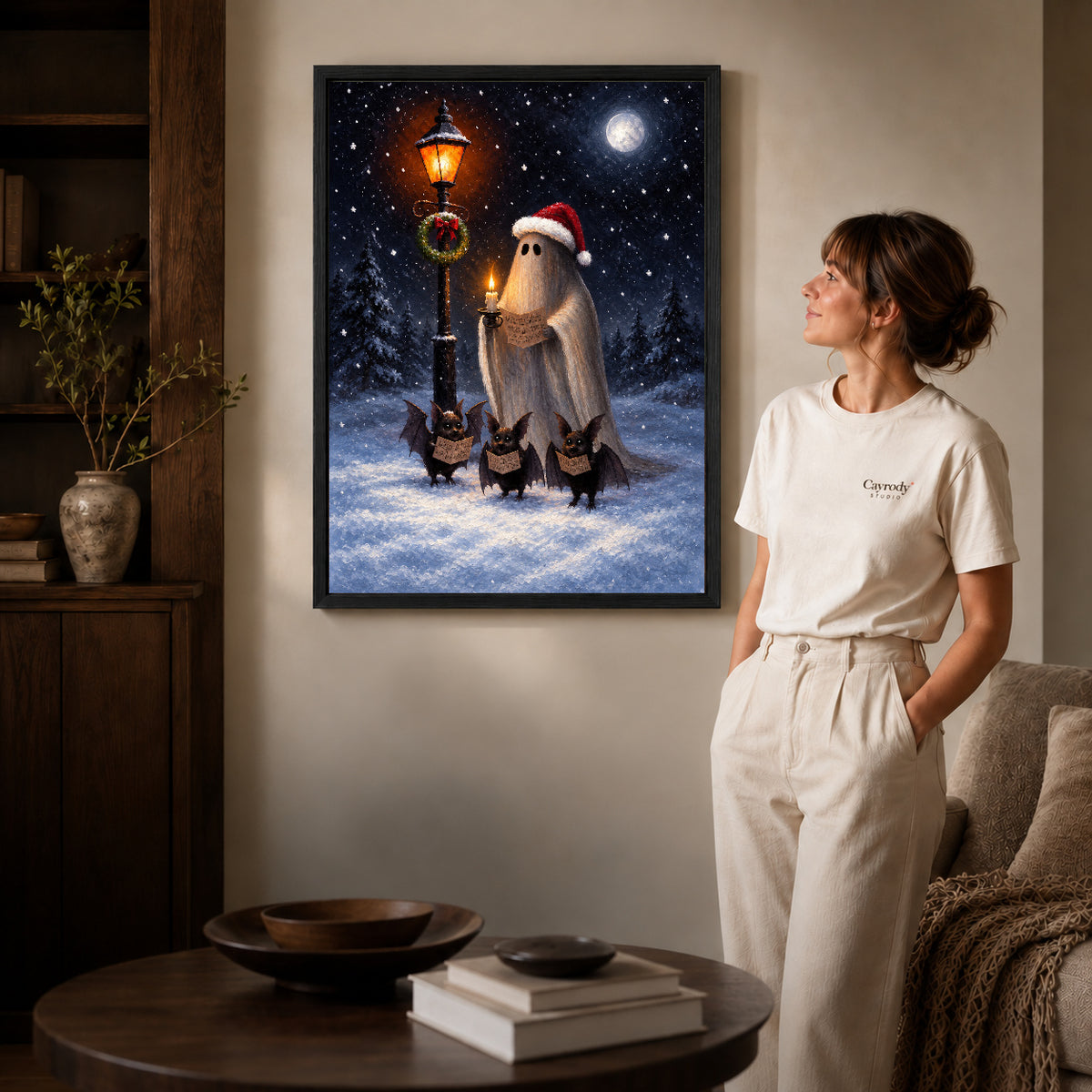 festive ghost choir canvas art in a black frame beside a woman and round wooden table.