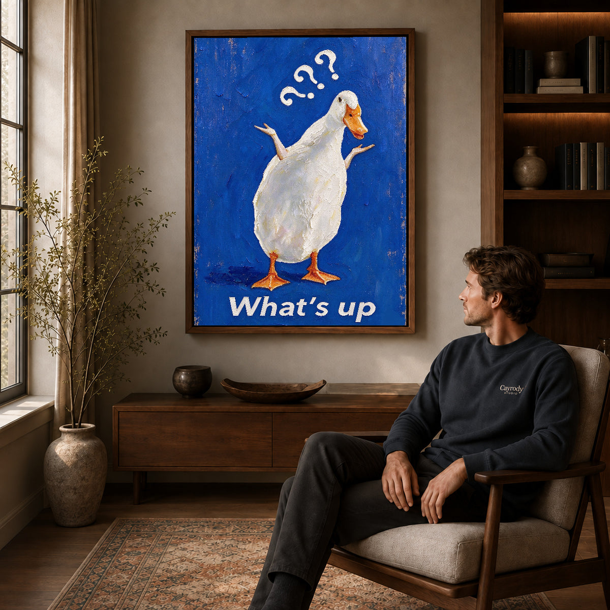 curious shrugging duck canvas art in a walnut frame above a console beside a seated man.