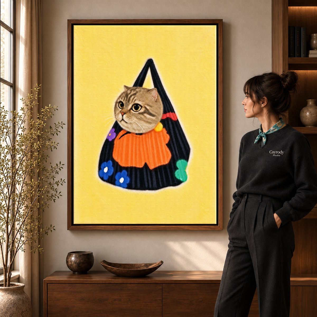tabby tote companion canvas art in a walnut frame beside a standing woman and wooden console.