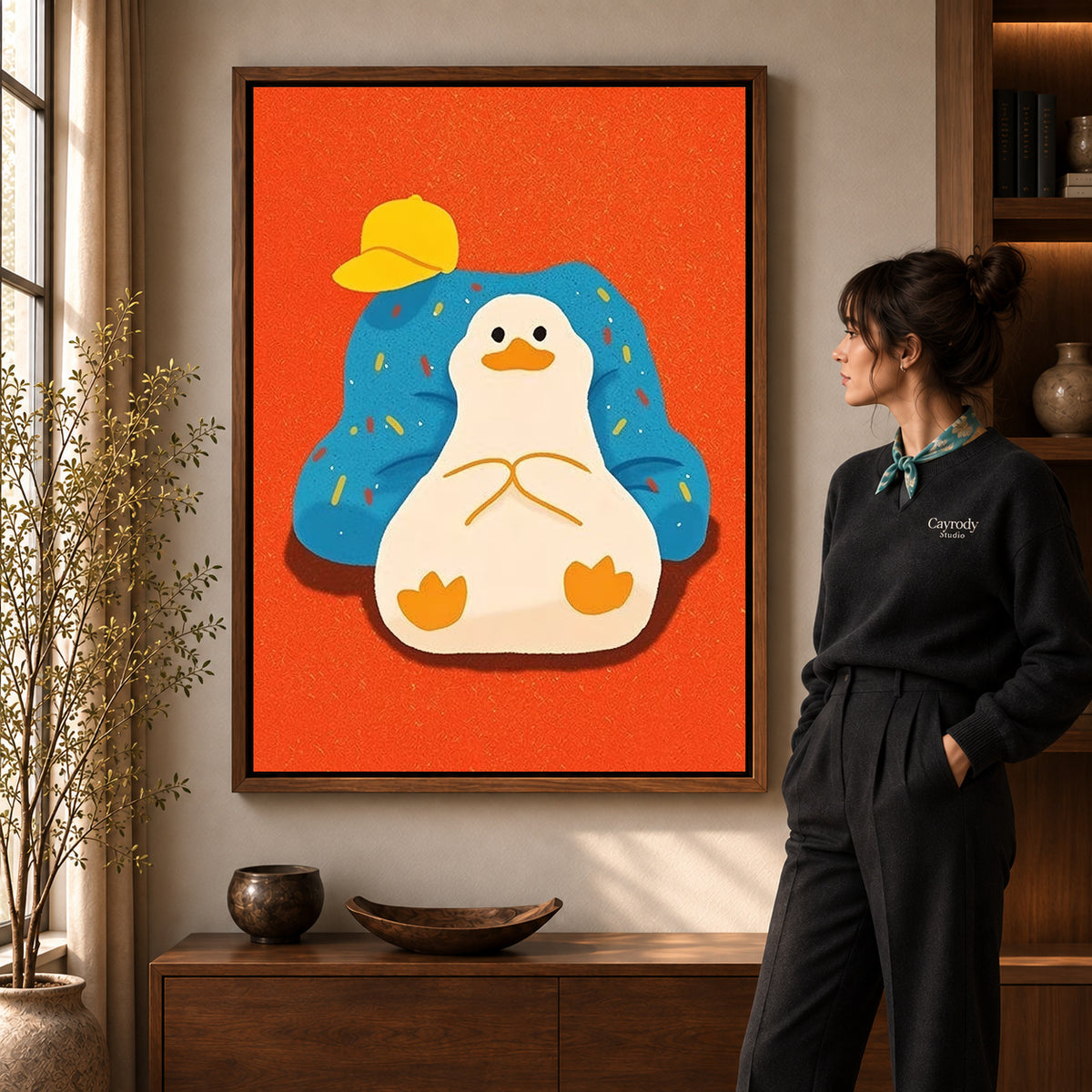 relaxed armchair duck canvas art in a walnut frame beside a standing woman and wooden console.